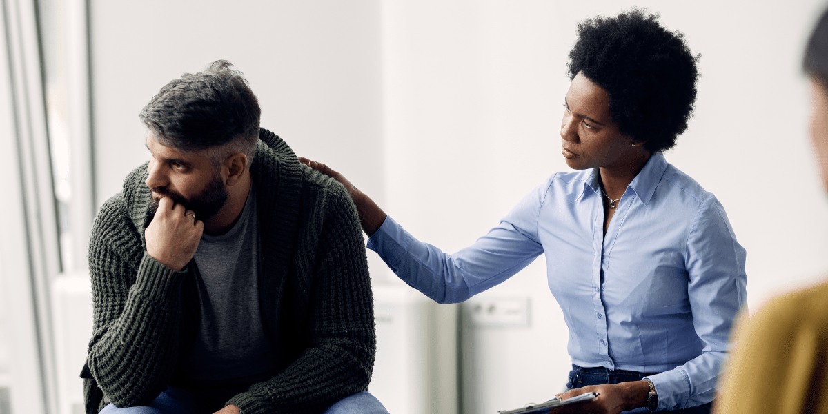 woman comforting man in therapy session