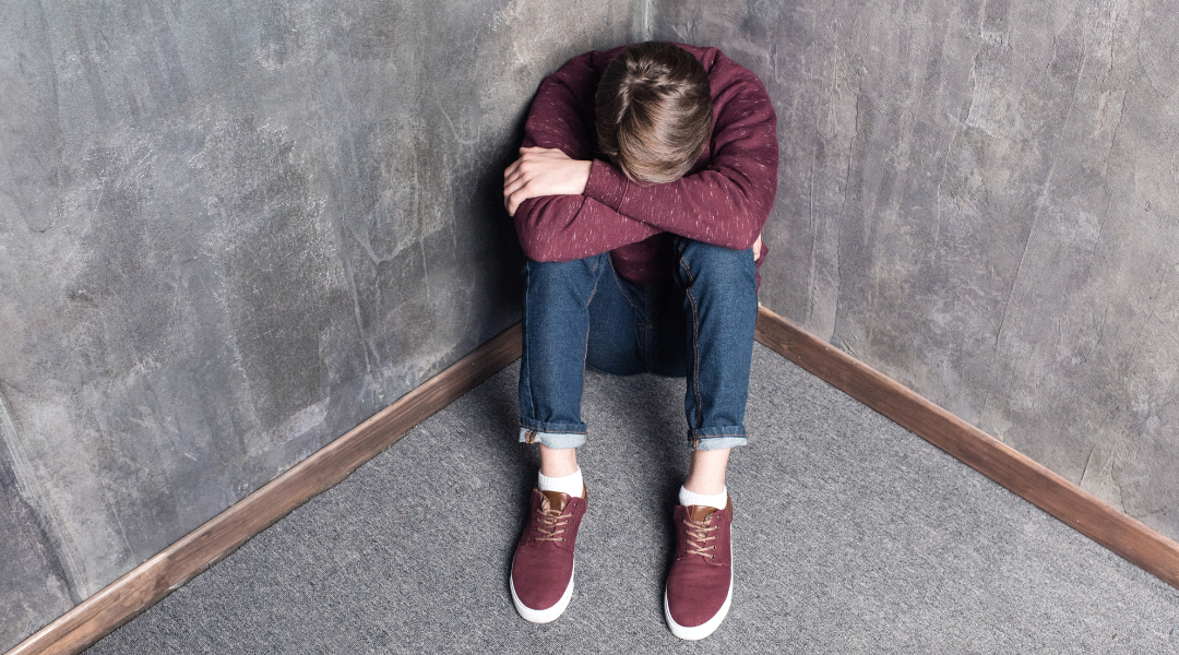 a teenager sitting in the corner of the wall going through teenage depression