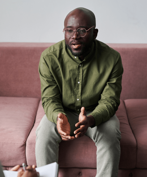 man sitting on red couch talking to therapist