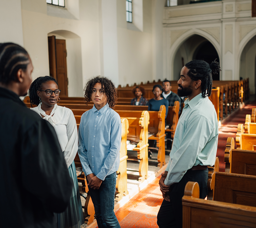 African american family standing and listening to priest in church