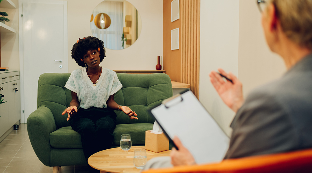 An african american woman is sitting with her psychotherapist at IOP facility