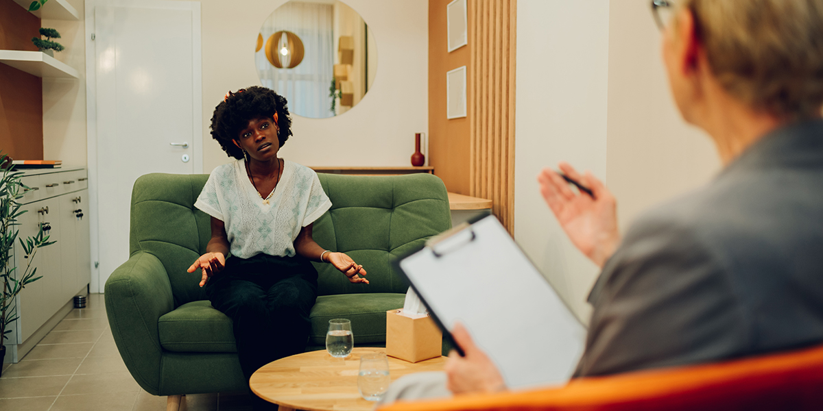 An african american woman is sitting with her psychotherapist at IOP facility