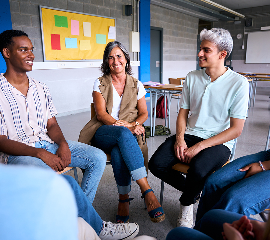 Diverse group of high school students sitting on chairs in a circle and interacting during a lesson