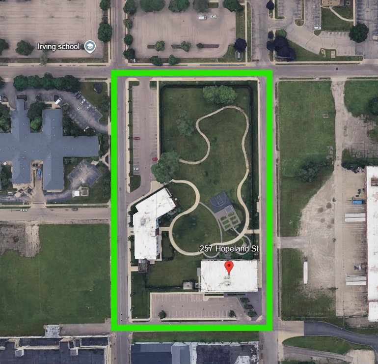 Aerial view of a campus-like complex bounded by neon-green borders, with a winding path on the lawn and a white building at 257 Hopeland St.